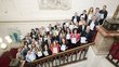 Die Gewinnerinnen und Gewinner des Gütesiegels stehen auf einer Treppe gemeinsam mit dem Bildungsminister Polaschek. Alle halten ihre Urkunden hoch. Das Bild ist von oben gemacht worden.