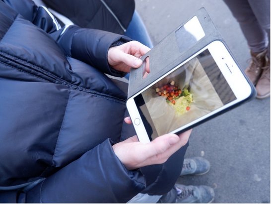 Person fotografiert den Lebensmittel Einkauf in einer Plastiktüte mit dem Smartphone