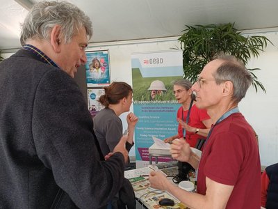 Zwei Männer im Austausch vor einem Infostand