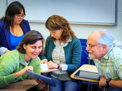 Vier Menschen arbeiten an Tablets und tauschen sich aus