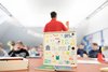 CO2-Spiel der evn. Im Hintergrund zeigt ein Erwachsener Schüler/innen eine Karte