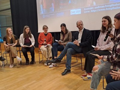 Schülerinnen und Schüler mit Wissenschaftsbotschafter bei einer Podiumsdiskussion