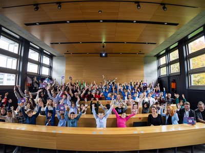 Young Science-Kongress 2025 Schüler/innen, Lehrpersonen und Schulleitungen halten ihre Tafeln hoch und jubeln über den Gewinn