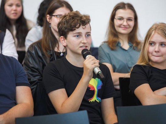 ein Schüler stellt mit Mikrophon eine Frage