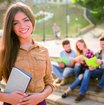 Mädchen hält ein Buch in der Hand, im Hintergrund sind drei Studierende